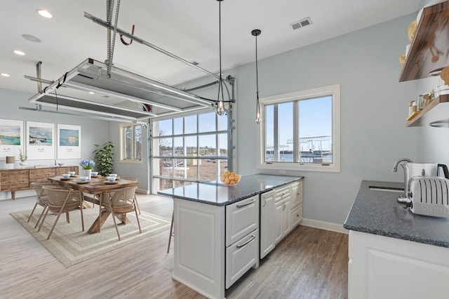 kitchen featuring white cabinets, light wood-style floors, recessed lighting, baseboards, and dark stone countertops