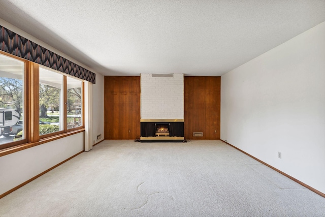 unfurnished living room featuring light colored carpet, a textured ceiling, a brick fireplace, and baseboards