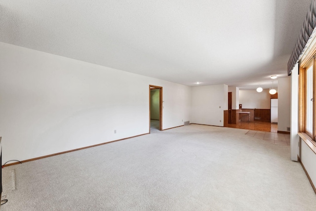 unfurnished living room featuring light carpet and baseboards