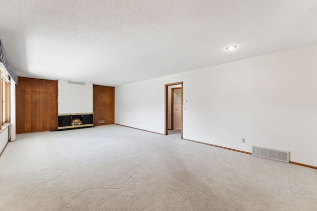 unfurnished living room with light carpet, a multi sided fireplace, baseboards, and a textured ceiling