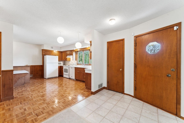 kitchen featuring freestanding refrigerator, range, light countertops, brown cabinets, and a textured ceiling