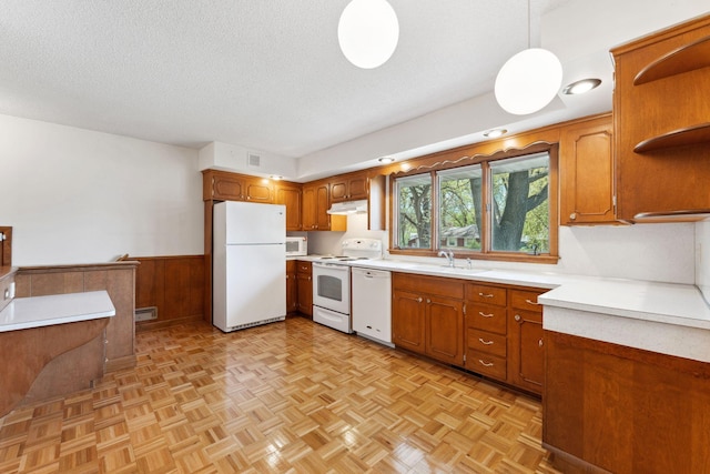 kitchen with white appliances, under cabinet range hood, open shelves, brown cabinets, and light countertops