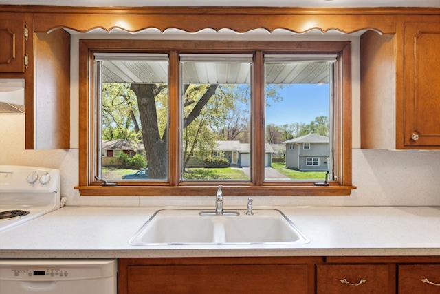 kitchen featuring white appliances, a sink, brown cabinets, and light countertops