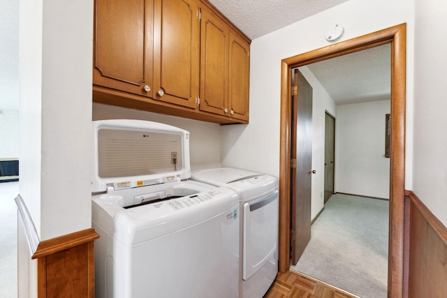 laundry room featuring cabinet space, a textured ceiling, and washer and dryer