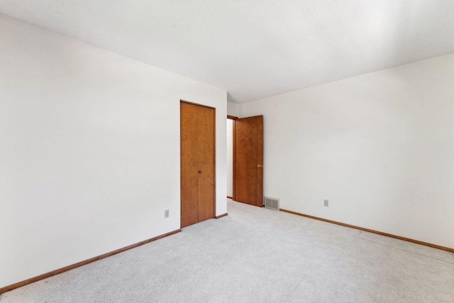 empty room featuring light carpet and baseboards