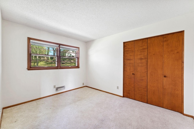 unfurnished bedroom with carpet flooring, a textured ceiling, a closet, and baseboards