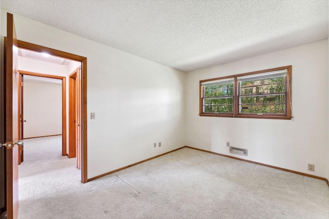 carpeted spare room with a textured ceiling and baseboards