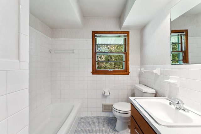 bathroom with tile walls, plenty of natural light, tile patterned floors, toilet, and vanity