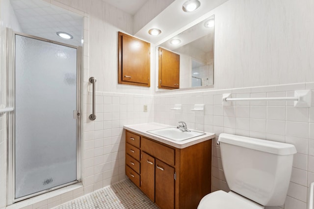 bathroom featuring tile patterned floors, tile walls, a shower stall, toilet, and vanity