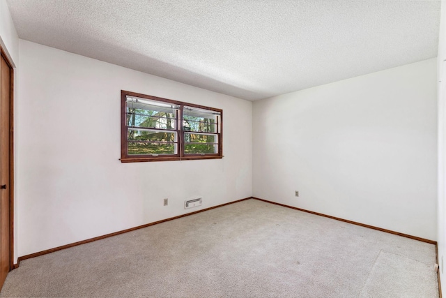 carpeted empty room with a textured ceiling and baseboards