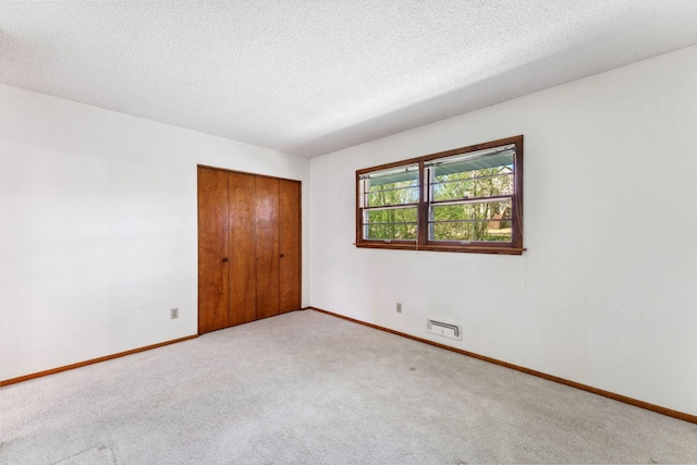 unfurnished bedroom featuring carpet flooring, a closet, baseboards, and a textured ceiling