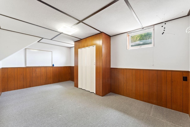 basement featuring wood walls, a wainscoted wall, and carpet