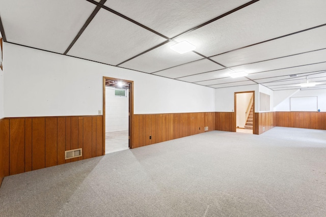 finished below grade area with wainscoting, wood walls, stairway, and carpet