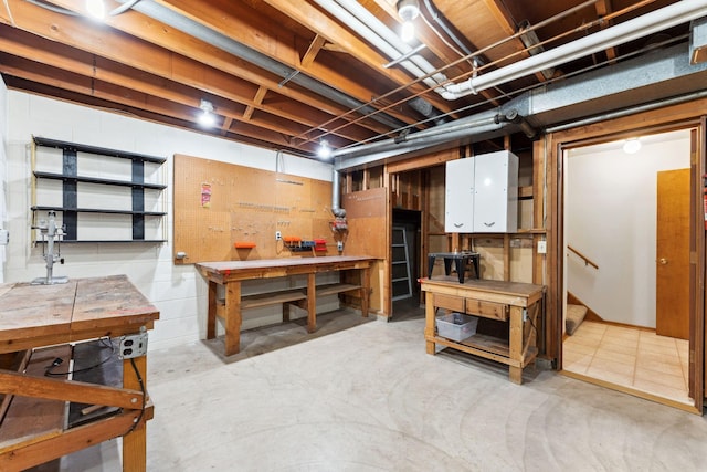 unfinished basement featuring a workshop area and stairway