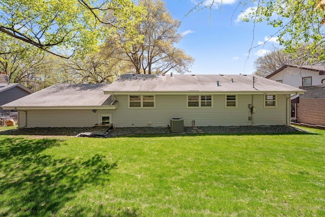 rear view of property with central AC unit and a yard