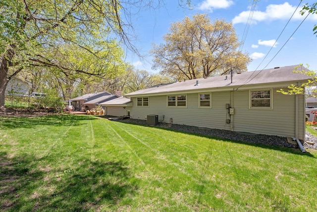 rear view of property featuring central air condition unit and a yard