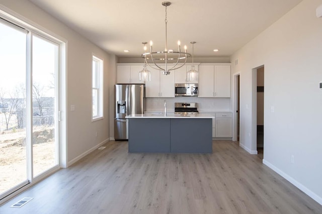 kitchen with visible vents, light wood finished floors, appliances with stainless steel finishes, and white cabinetry