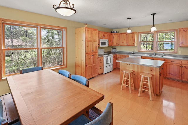 10209 Amery Ave NW, Silver Creek Twp, MN 55362 - kitchen with white appliances, a sink, a kitchen island, pendant lighting, and light wood-style flooring