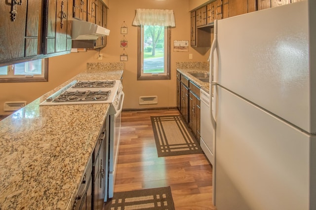 10929 108th Ave N, Maple Grove, MN 55369 - kitchen featuring white appliances, range hood, light wood-style flooring, brown cabinetry, and light stone counters