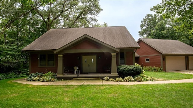view of front facade featuring a shingled roof, a garage, a porch, a front yard, and driveway