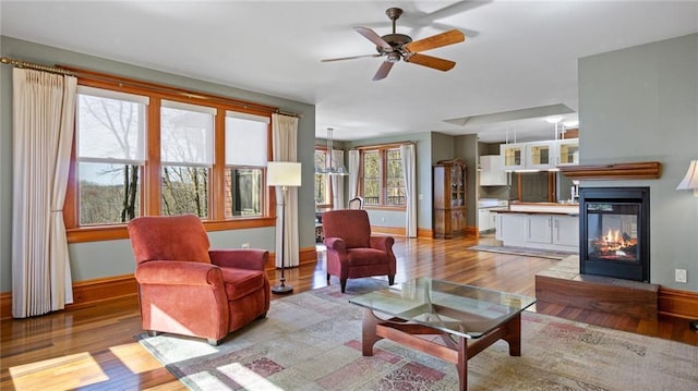 living room with light wood-style floors, baseboards, and ceiling fan