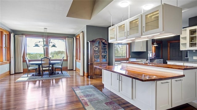 kitchen featuring a sink, butcher block countertops, white cabinetry, baseboards, and dark wood-style floors