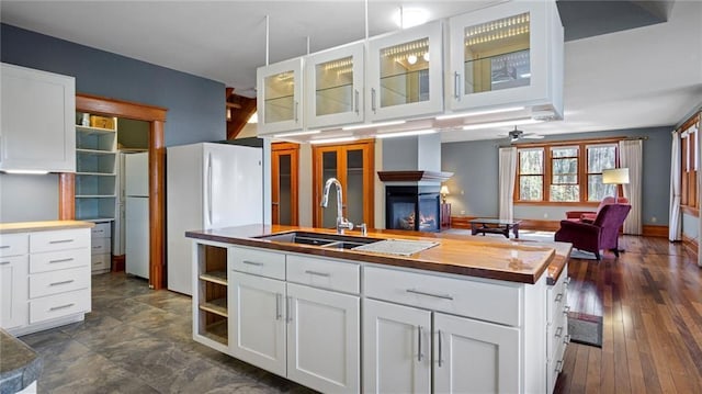 kitchen with white cabinets, open floor plan, ceiling fan, and a sink