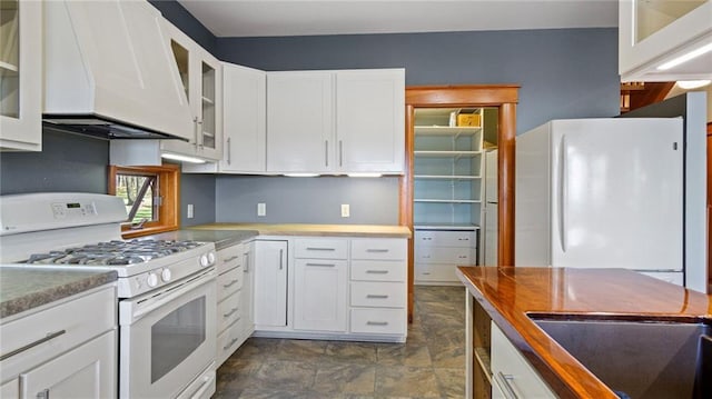 kitchen with glass insert cabinets, range hood, white appliances, and white cabinetry