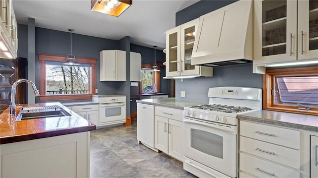 kitchen featuring a sink, white cabinetry, premium range hood, and white appliances