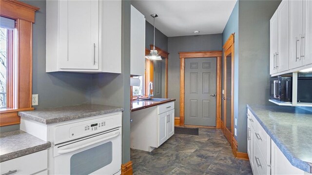 kitchen featuring white cabinets, oven, black microwave, and a sink