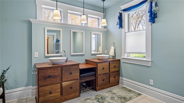 bathroom with double vanity, a sink, baseboards, and tile patterned flooring