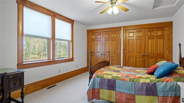 bedroom featuring visible vents, two closets, baseboards, ceiling fan, and carpet flooring