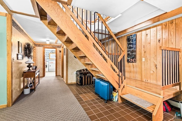 stairway with separate washer and dryer, baseboards, and wood walls