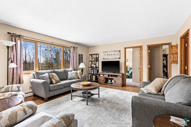 living room with a textured ceiling, light wood-style flooring, and a baseboard radiator