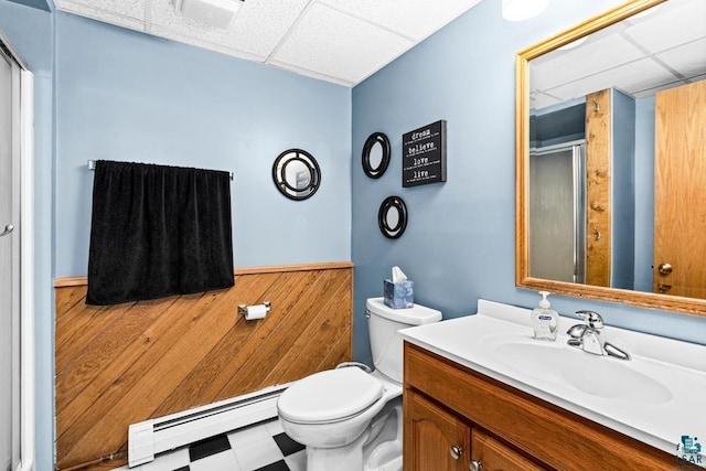 bathroom with baseboard heating, vanity, toilet, a paneled ceiling, and a stall shower