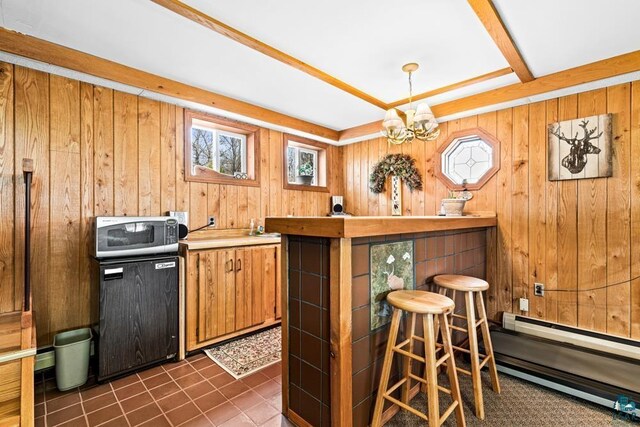 bar featuring wood walls, pendant lighting, a baseboard heating unit, a chandelier, and dark tile patterned flooring
