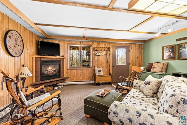 living room with carpet, wooden walls, and a tile fireplace