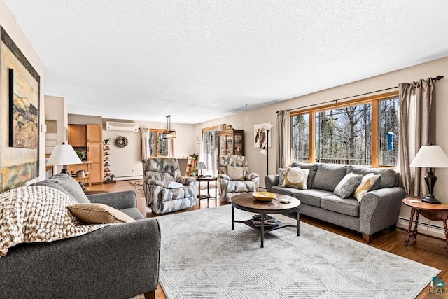 living area featuring wood finished floors, a textured ceiling, a baseboard heating unit, a wall mounted AC, and a baseboard radiator