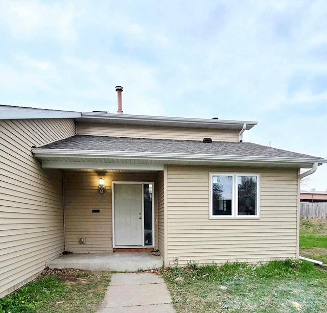doorway to property with roof with shingles
