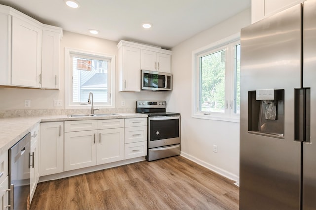 601 Harry Davis Ln, Minneapolis, MN 55411 - kitchen with appliances with stainless steel finishes, a sink, white cabinets, light wood finished floors, and baseboards