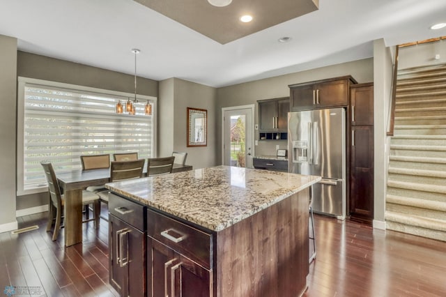 kitchen featuring a kitchen island, stainless steel fridge, light stone counters, and dark wood-style floors