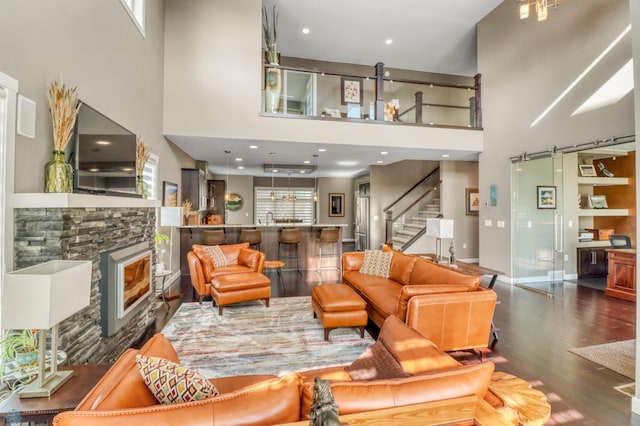 living area with wood finished floors, a high ceiling, a fireplace, baseboards, and stairs