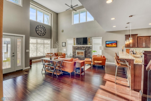 living room with recessed lighting, baseboards, ceiling fan, a towering ceiling, and a fireplace