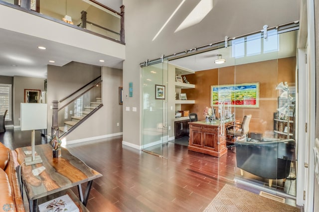 interior space with a towering ceiling, wood finished floors, baseboards, and a healthy amount of sunlight