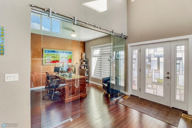 office space featuring baseboards, a towering ceiling, and wood finished floors