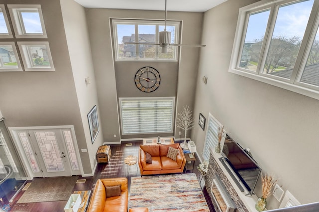 living area featuring a wealth of natural light, a high ceiling, and wood finished floors
