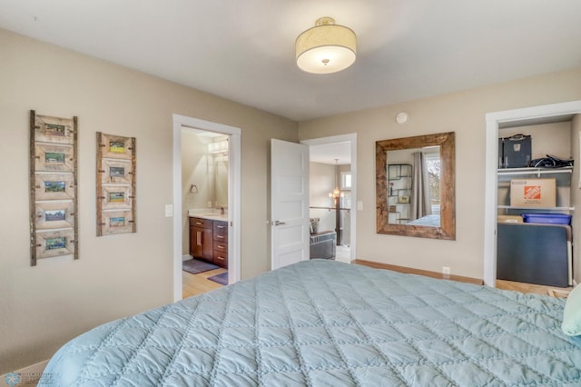 bedroom featuring baseboards, ensuite bathroom, and a sink