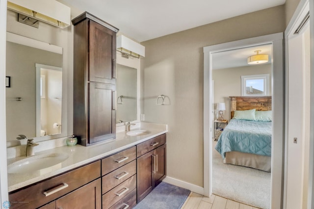 bathroom featuring baseboards, ensuite bathroom, double vanity, and a sink