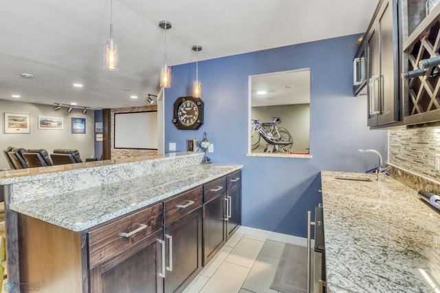 kitchen featuring a sink, a peninsula, light stone countertops, and decorative backsplash