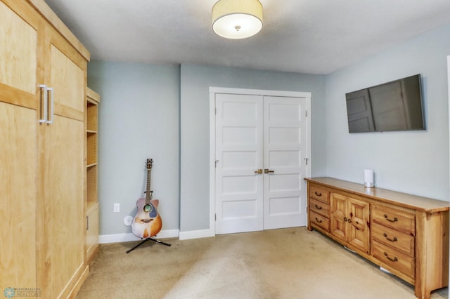 bedroom featuring light colored carpet, a closet, and baseboards